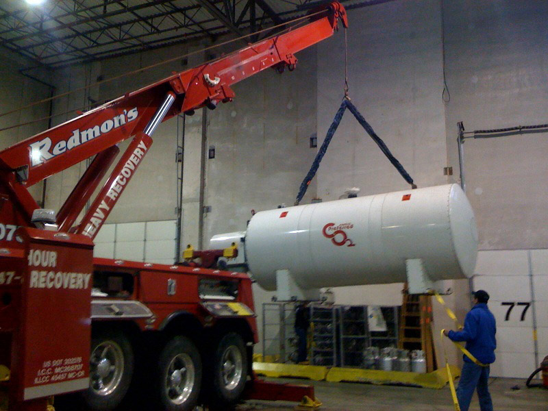 Large tank being lifted by a crane in a large warehouse